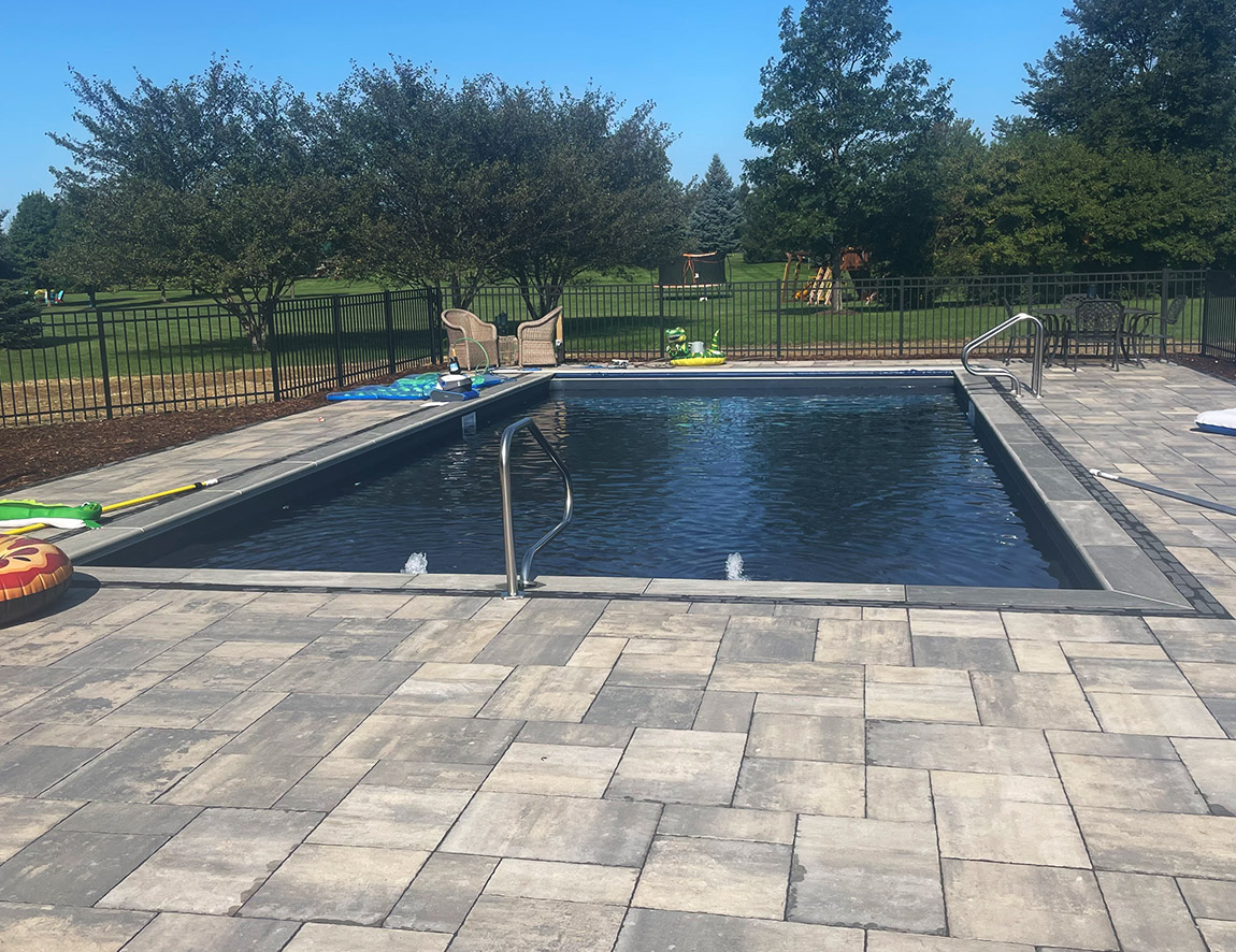 a photo of a completed pool done by pool installation contractors in new berlin wi. stone and trees surrounding the pool.