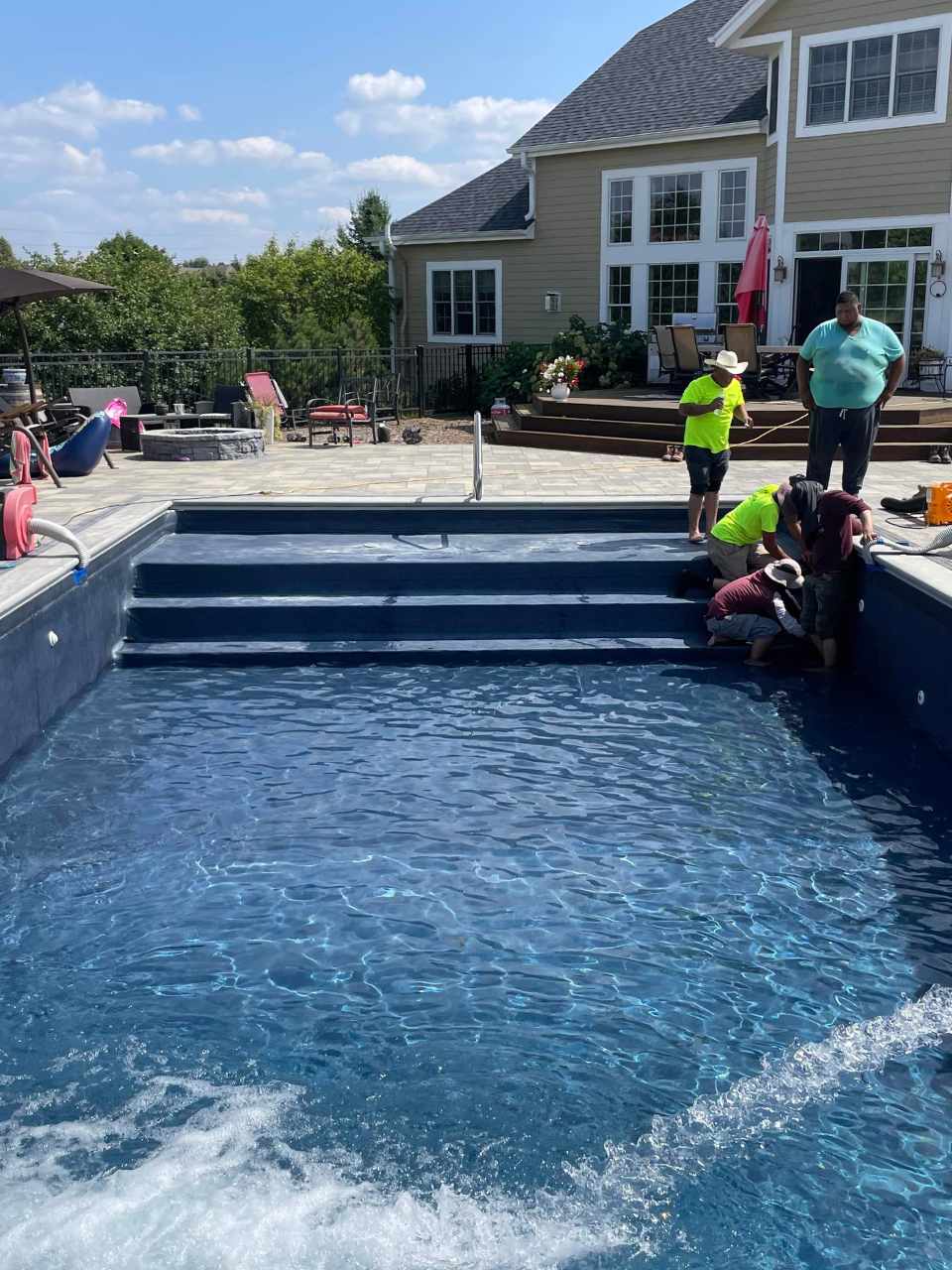 Final stages of a new pool installation in Hartland with workers finishing details and water already filled in the pool.