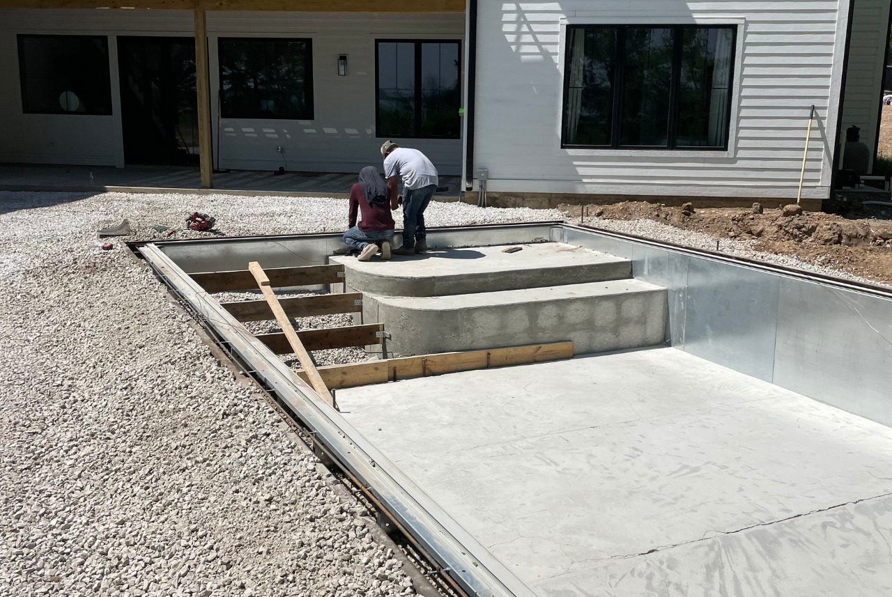Construction workers building a new swimming pool, demonstrating the quality work of the best pool builder in Waukesha, WI.