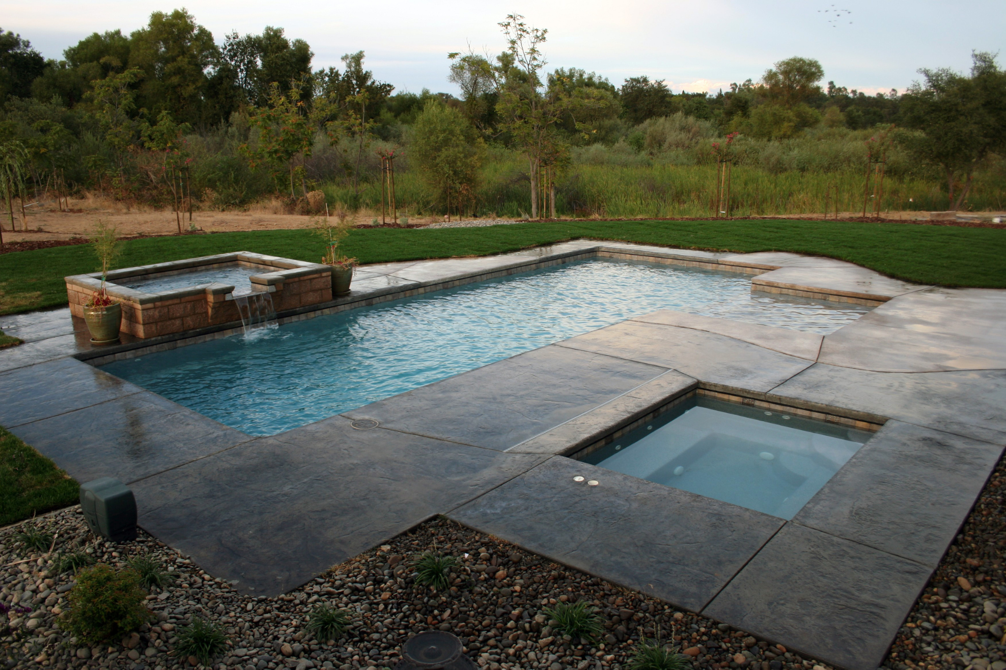 spillover spa into pool, custom designed by loomis pools. rock landscaping.